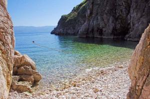 a body of water with a rocky shore with a mountain at Apartment in Vrbnik - Insel Krk 13622 in Vrbnik +16 photos