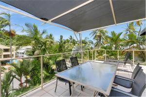a table and chairs on a balcony with palm trees at Seascape Holidays - Driftwood Mantaray in Port Douglas