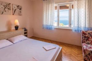 a bedroom with a bed and a window and a chair at Apartment in Vrbnik/Insel Krk 13616 in Vrbnik