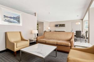 カルガリーにあるBest Western Premier Calgary Plaza Hotel & Conference Centreのソファと椅子とテーブルのあるリビングルーム