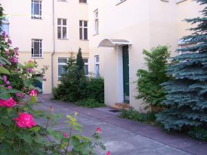 ein weißes Gebäude mit grüner Tür und ein paar Blumen in der Unterkunft Hotel Pension Streuhof Berlin in Berlin