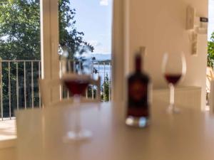 two glasses of wine sitting on a table with a window at Apartment in Njivice/Insel Krk 27658 in Njivice