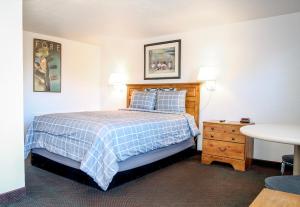 1 dormitorio con 1 cama con manta azul y blanca en Baker City Motel & RV, en Baker City