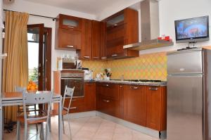 a kitchen with wooden cabinets and a table and a refrigerator at Domo - Guest-House Il Nespolo Fiorito in Orosei