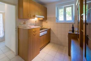 a kitchen with wooden cabinets and a sink and a window at Three-Bedroom Holiday Home in Crikvenica II in Sopaljska