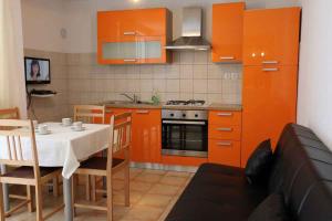a kitchen with orange cabinets and a table with a white table cloth at Apartment in Silo/Insel Krk 13550 in Šilo