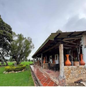 een huis met een veranda met oranje vazen erop bij GhuRu Hotel Campestre in Firavitoba