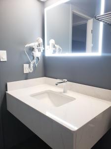 ein Badezimmer mit einem weißen Waschbecken und einem Spiegel in der Unterkunft Moonlight Inn and Suites Sudbury in Sudbury