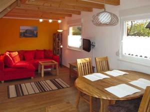 ein Wohnzimmer mit einem Tisch und einem roten Sofa in der Unterkunft Holiday home in Zinnowitz (Seebad) 33031 in Zinnowitz