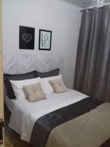 1 dormitorio con 1 cama grande con sábanas y almohadas blancas en Kitnet Recanto de Campos-Pertinho do Centro en Campos do Jordão