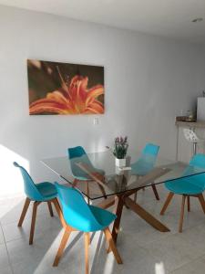 a dining room with a glass table and blue chairs at Hermosa Casa Vacacional Puerto Morelos in Puerto Morelos