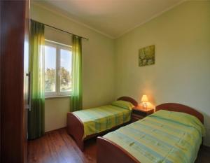 2 camas en una habitación con cortinas verdes y ventana en Apartments Marinko-with pool, en Barban