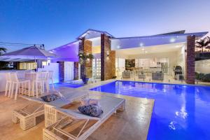 a swimming pool with chairs and a table in a house at Exquisite Riverside Living, Noosaville in Noosaville