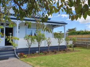 uma casa branca com árvores no jardim da frente em Fossil Coast B&B em Hawera