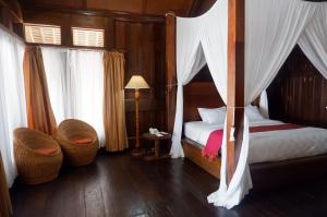 sypialnia z łóżkiem z baldachimem i wiklinowymi krzesłami w obiekcie Wakatobi Patuno Diving and Beach Resort by SAHID w mieście Wanci