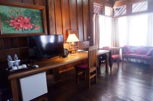 a room with a desk with a television and a living room at Wakatobi Patuno Diving and Beach Resort by SAHID in Wanci