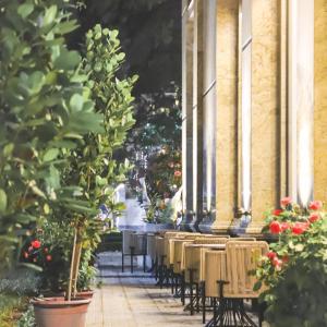 a row of chairs sitting outside of a building with flowers at Mansion Park Hotel & Apartment in Bien Hoa