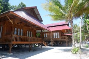 a building on the beach with a palm tree at Wakatobi Patuno Diving and Beach Resort by SAHID in Wanci