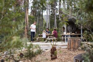 eine Gruppe von Menschen, die an einem Picknicktisch im Wald sitzen in der Unterkunft River Run Lodge in Strathblane