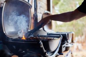 a person cooking food in a pan on a grill at River Run Lodge in Strathblane