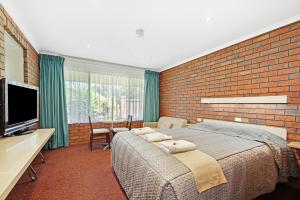 1 dormitorio con 1 cama grande y pared de ladrillo en Golden Country Motel and Caravan Park, en Maryborough