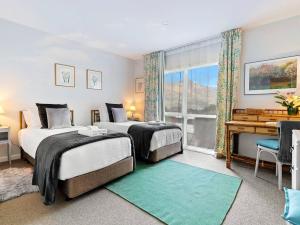 a bedroom with two beds and a desk and a window at Central Location - 2 Bedroom Apartment in Habeke in Queenstown