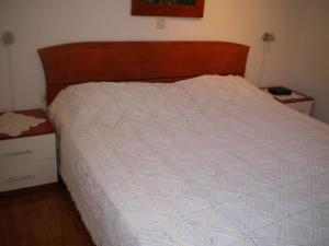 a bed with a white comforter and a wooden head board at Apartment Milan - 10 m from the sea in Drvenik Veli