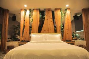 um quarto com uma cama branca e postes de madeira em OHYA Chain Boutique Motel-Xinying em Xinying