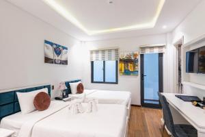 a hotel room with two beds and a desk at Hoang Trinh Hotel in Hoi An