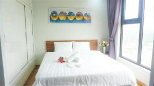 a bedroom with a white bed with flowers on it at Ecobay Halong -Mountain view and near Marina beach in Ha Long +9 photos