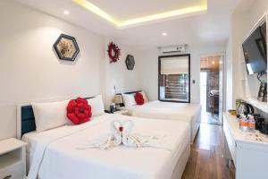 2 letti in una camera con pareti bianche di Hoang Trinh Hotel a Hoi An