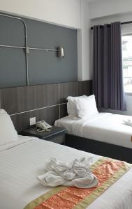ein Hotelzimmer mit 2 Betten mit weißer Bettwäsche in der Unterkunft The Inka Hotel in Nakhon Si Thammarat