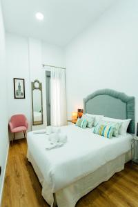 1 dormitorio con 1 cama blanca grande y 1 silla rosa en Modern with swimming pool- 1Bd 1Bth- Goyeneta, en Sevilla