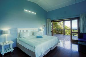 a blue bedroom with a bed and a balcony at Mar Azul 2 in Ponta Malongane