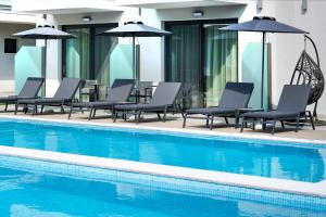 a group of chairs and umbrellas next to a swimming pool at Anassa Blue Boutique Hotel in Limenas