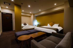 a hotel room with two beds and a couch at Randor Hotel Sapporo Suites in Sapporo