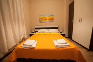 Un dormitorio con una gran cama amarilla con toallas. en Апартамент РОСИ, en Pleven