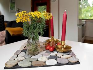 a table with a candle and a vase of flowers and rocks at 4 person holiday home in Gedser in Gedser