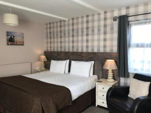 a bedroom with a large bed and a chair at The Cross Guest House in Mablethorpe