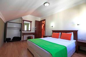 ein Schlafzimmer mit einem großen Bett mit orangefarbenen und grünen Kissen in der Unterkunft Sunlight Garden Hotel in Side