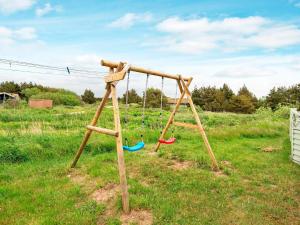 a swing set with three swings in a field at 6 person holiday home in R m in Bolilmark