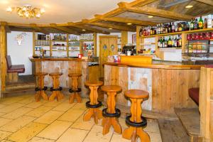 un bar dans un restaurant avec tabourets en bois dans l'établissement Hotel Bellevue, à Canazei
