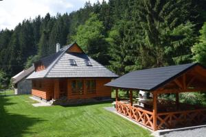 a log cabin with a black roof and a gazebo at Chata Romeo in Harmanec