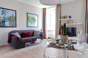 ein Wohnzimmer mit einem blauen Sofa und einem Glastisch in der Unterkunft Piazzetta Margutta - My Extra Home in Rom