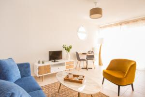 Zenao Appart'hôtels Villeneuve-lès-Avignon في فيلنوف-ليه-آفينيون: غرفة معيشة مع أريكة وكراسي زرقاء