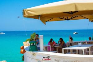 a group of people sitting at tables on the beach at I Sottani in Monopoli