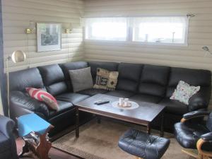 uma sala de estar com um sofá de couro preto e uma mesa em 5 person holiday home in Laukvik em Laukvik