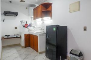 a kitchen with a black refrigerator and a sink at Spacious Classic 1BR Apartment at Taman Beverly By Travelio in Putat-gede