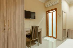 Habitación con escritorio, TV y silla. en Queen Inn Batam RedPartner, en Tanjungriau