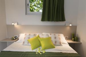 a bed with two yellow pillows and a window at Piani di Clodia Holidaypark in Lazise